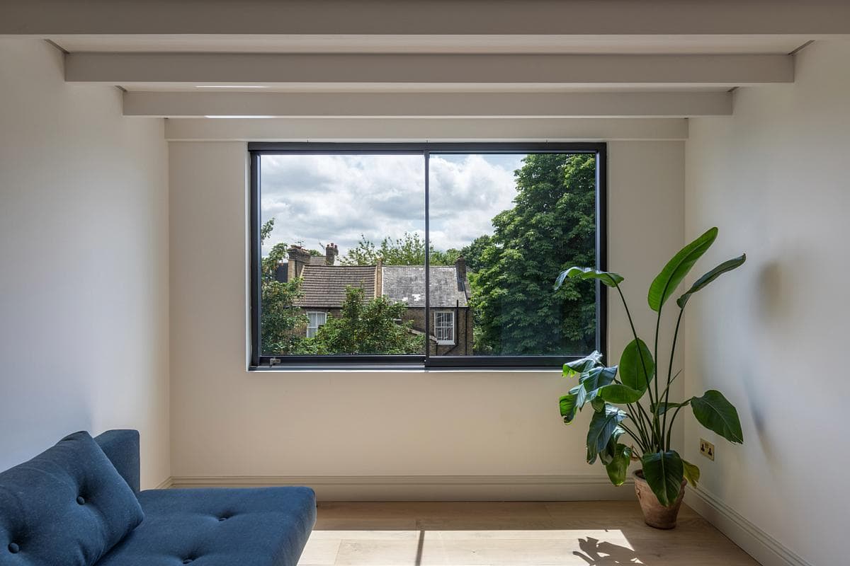 Stylish minimalist interior with natural light, a blue couch, and vibrant greenery.
