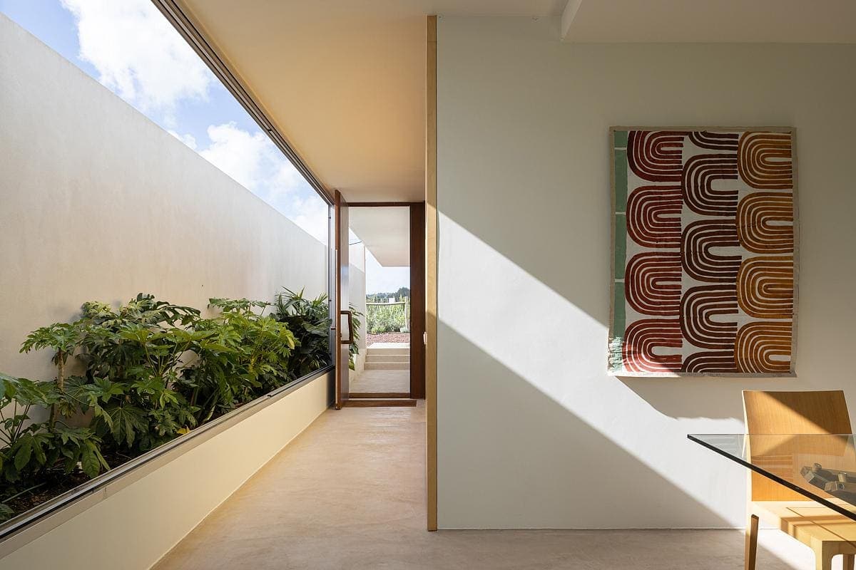 Modern minimalist interior with natural light, large windows, and earthy-toned artwork.