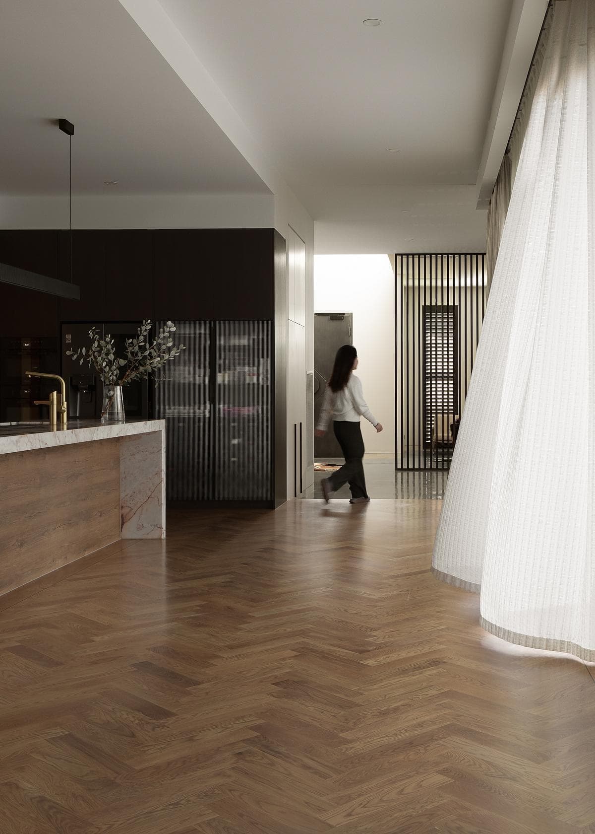 Contemporary kitchen with herringbone floors, marble island, and minimalist design elements.