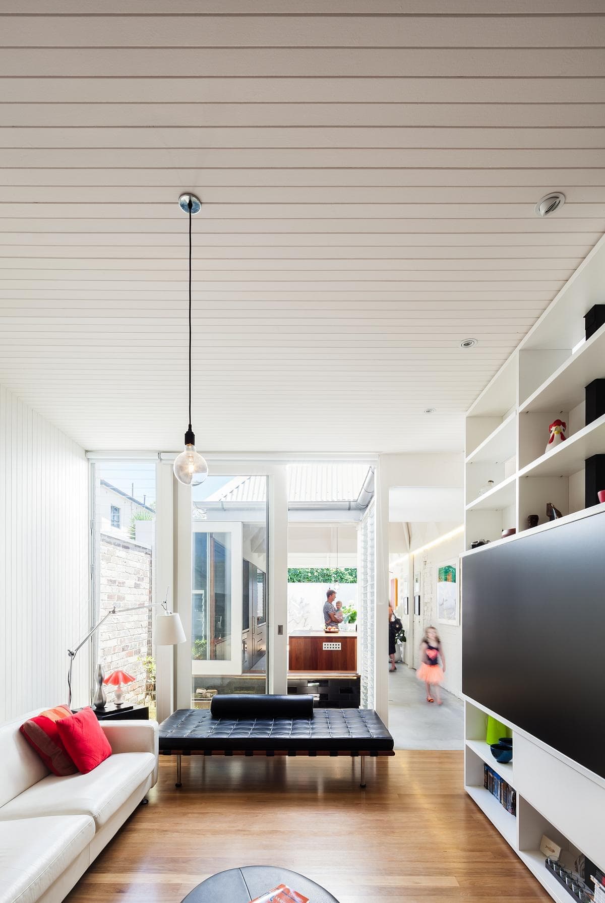 Bright minimalist living room with natural light, sleek furnishings, and warm wooden flooring.