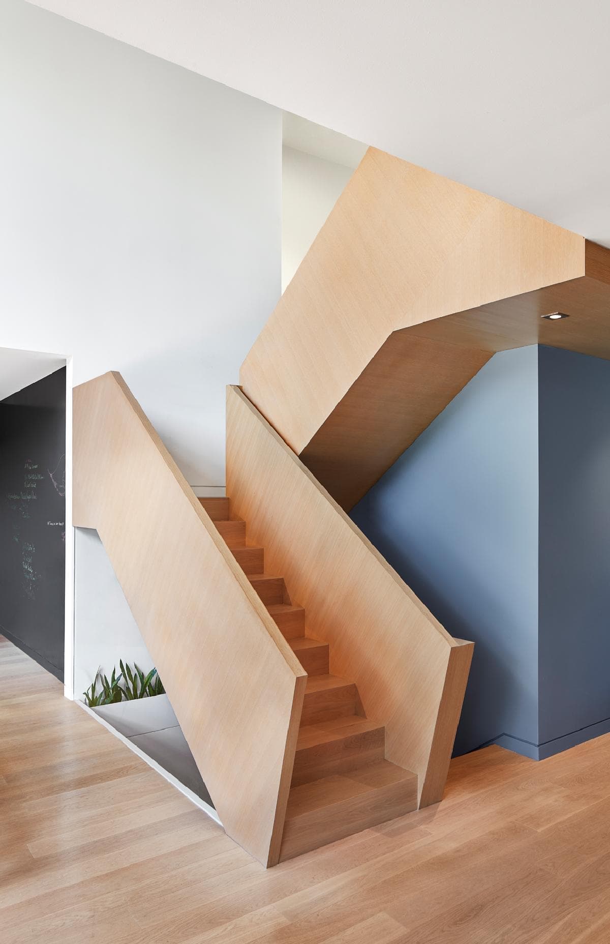 Modern minimalist staircase in contemporary interior with wood elements and contrasting walls.