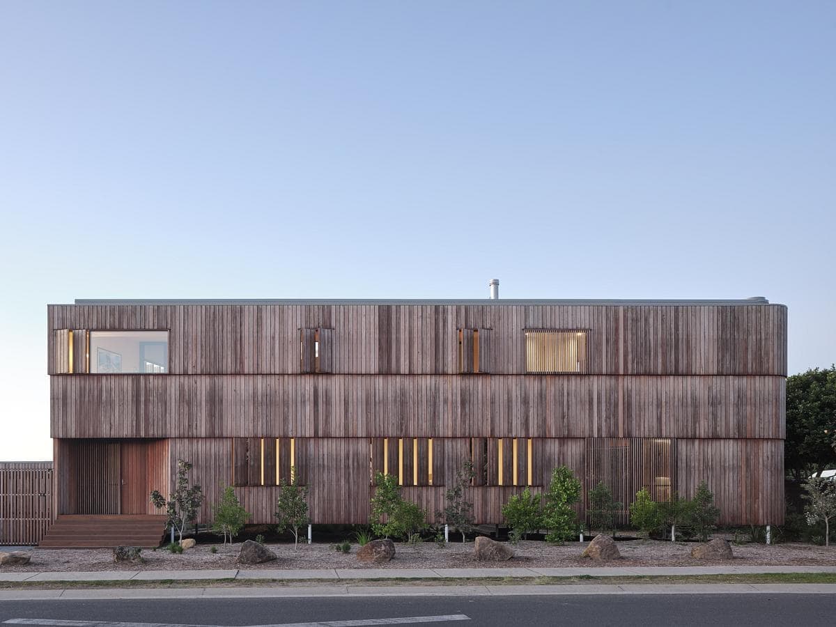 Modern minimalist wooden house with unique windows and a small front garden.