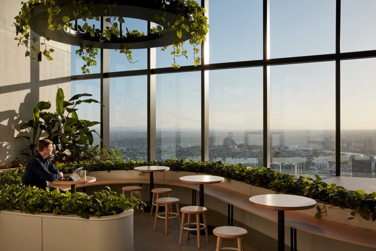 Modern office space with panoramic city view and greenery, fostering productivity and relaxation.
