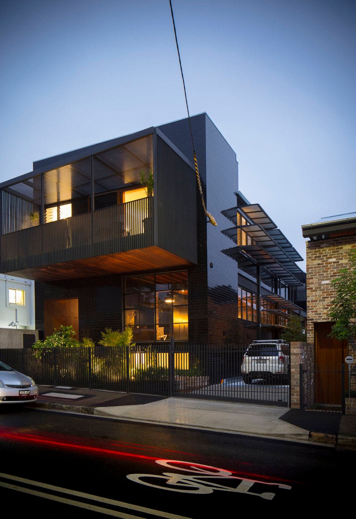 Contemporary urban home with elegant design and vibrant garden, illuminated at dusk.