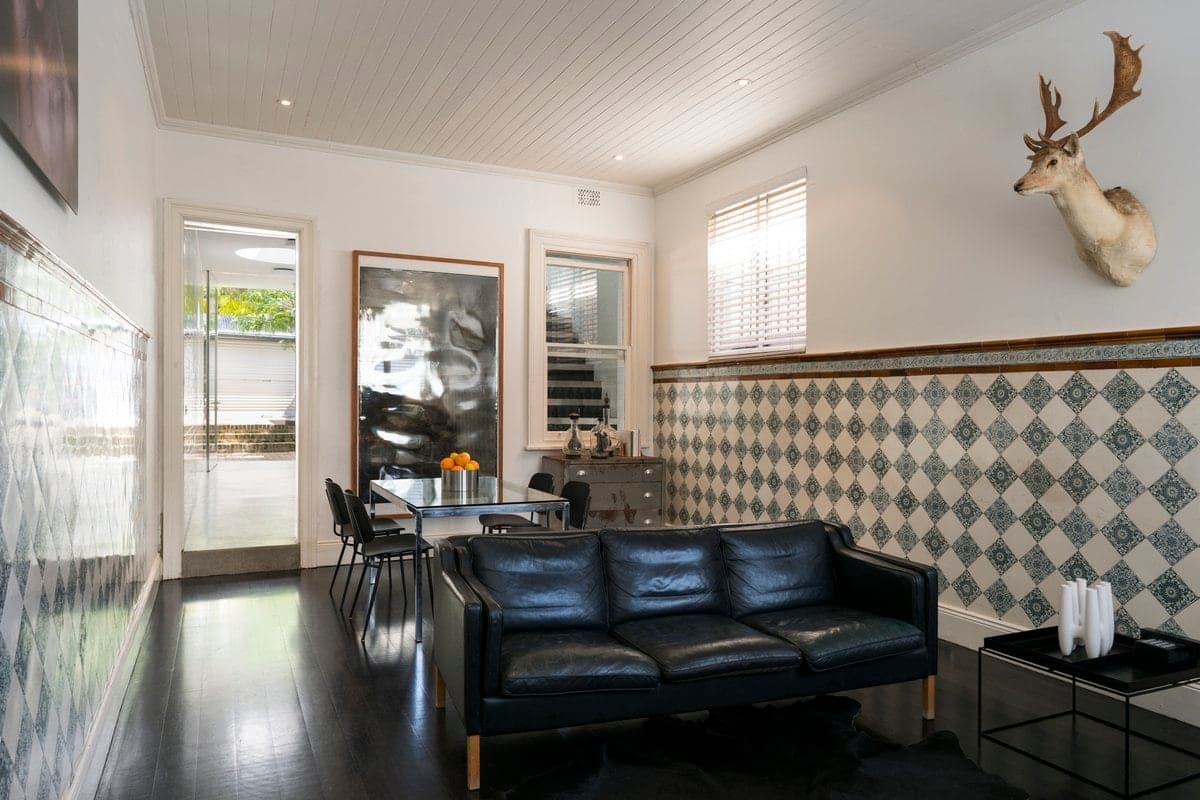 Modern living and dining room with rustic accents, white walls, black furniture, and natural light.