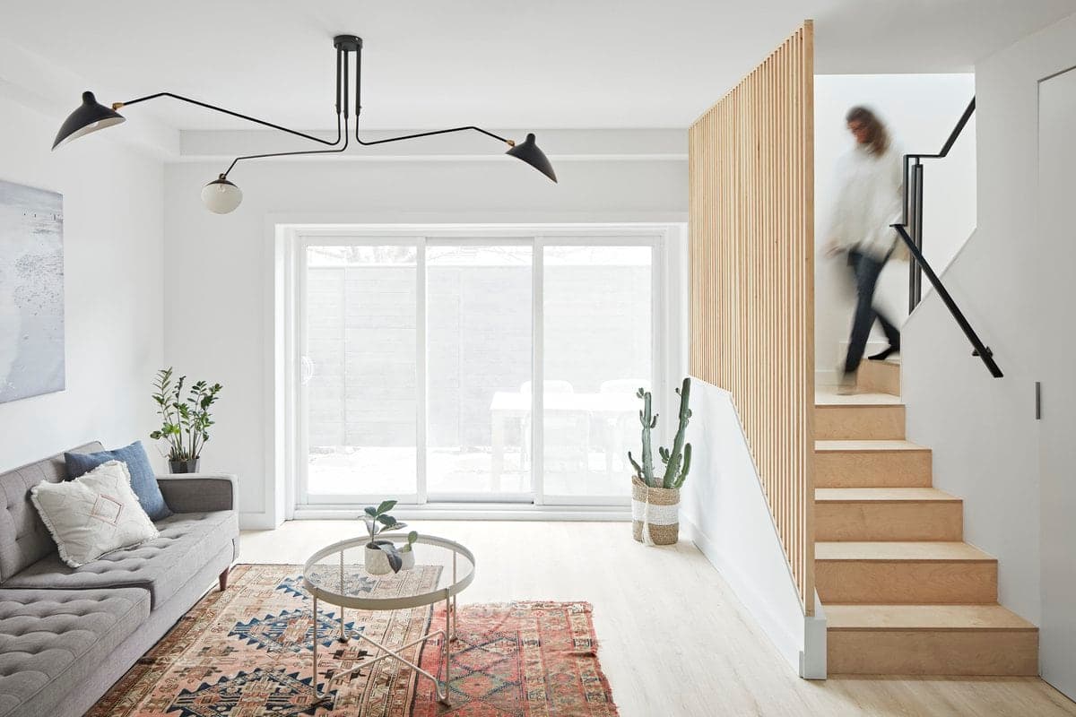 Living room with a grey sofa, glass table and large windows.
