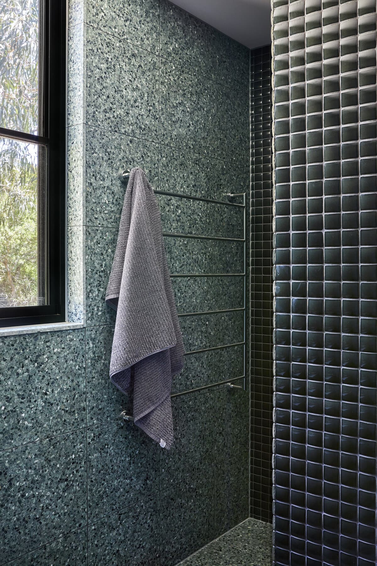 Stylish shower oasis featuring natural light and deep green tile design for relaxation.