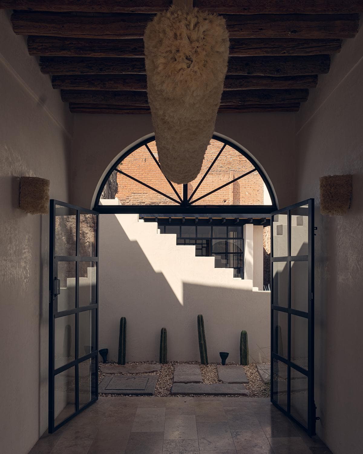 Stylish entryway featuring modern doors and a serene courtyard with cacti and stepping stones.