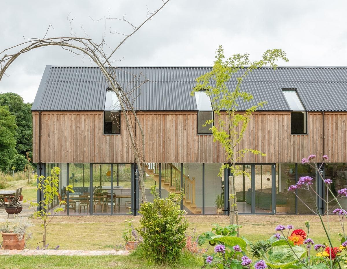Contemporary wooden house blending with nature, featuring large windows and a beautifully landscaped garden.