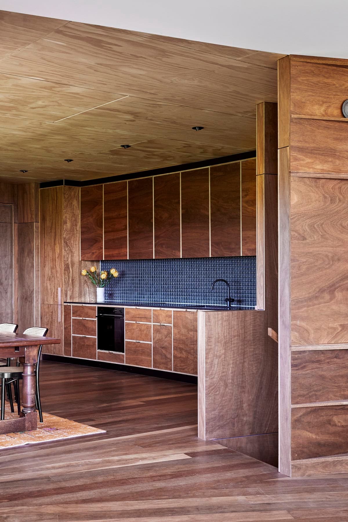 Elegant wooden kitchen and dining area with modern design and natural light.