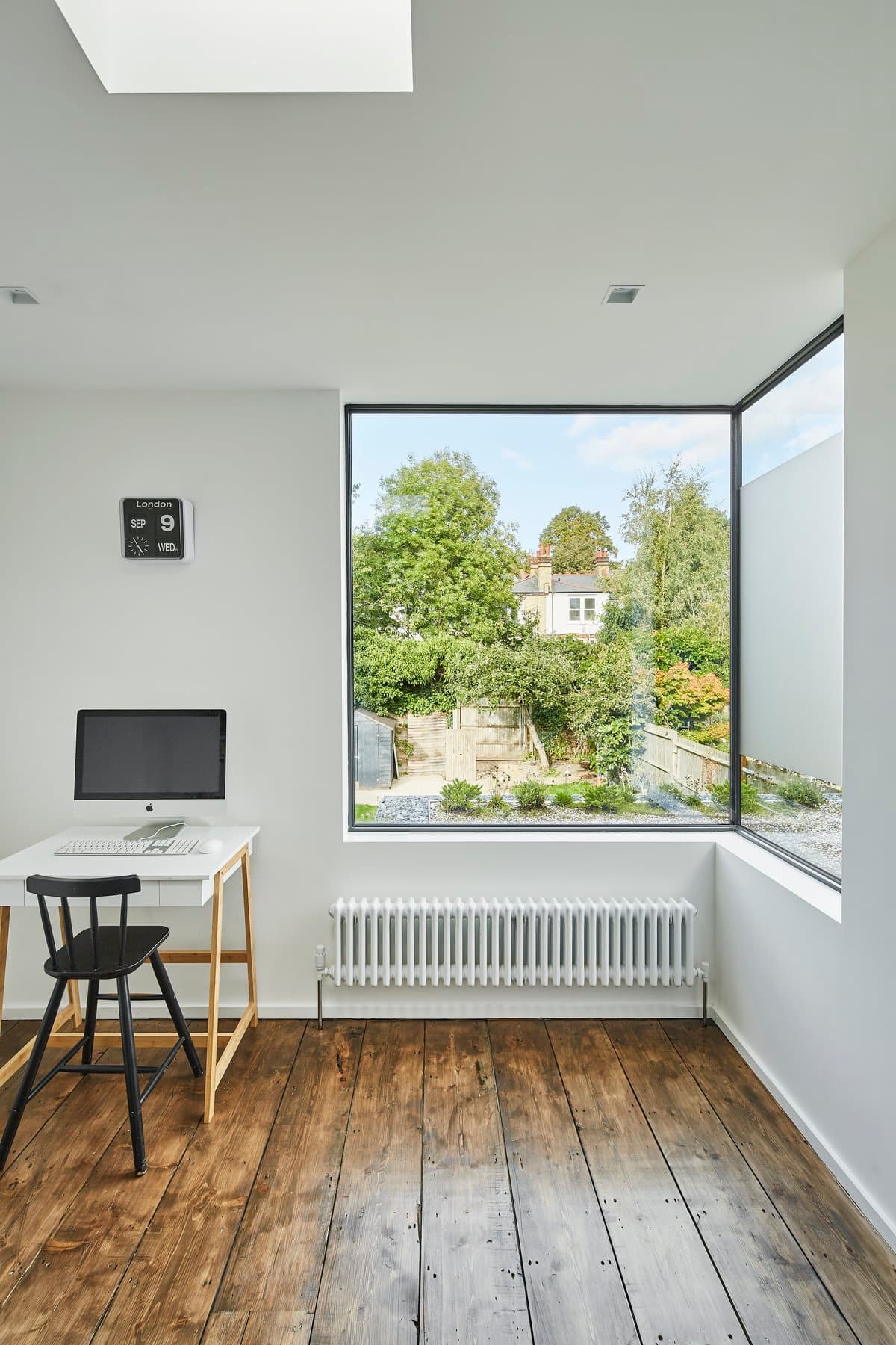 Minimalist modern workspace with natural light, polished wood flooring, and garden view.