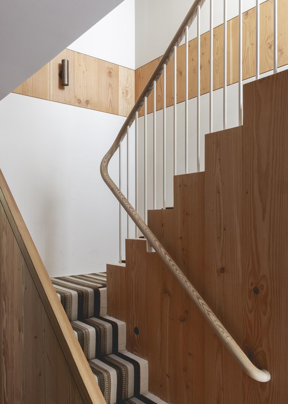 Stylish wooden staircase with a carpet runner, blending modern minimalism and natural warmth.