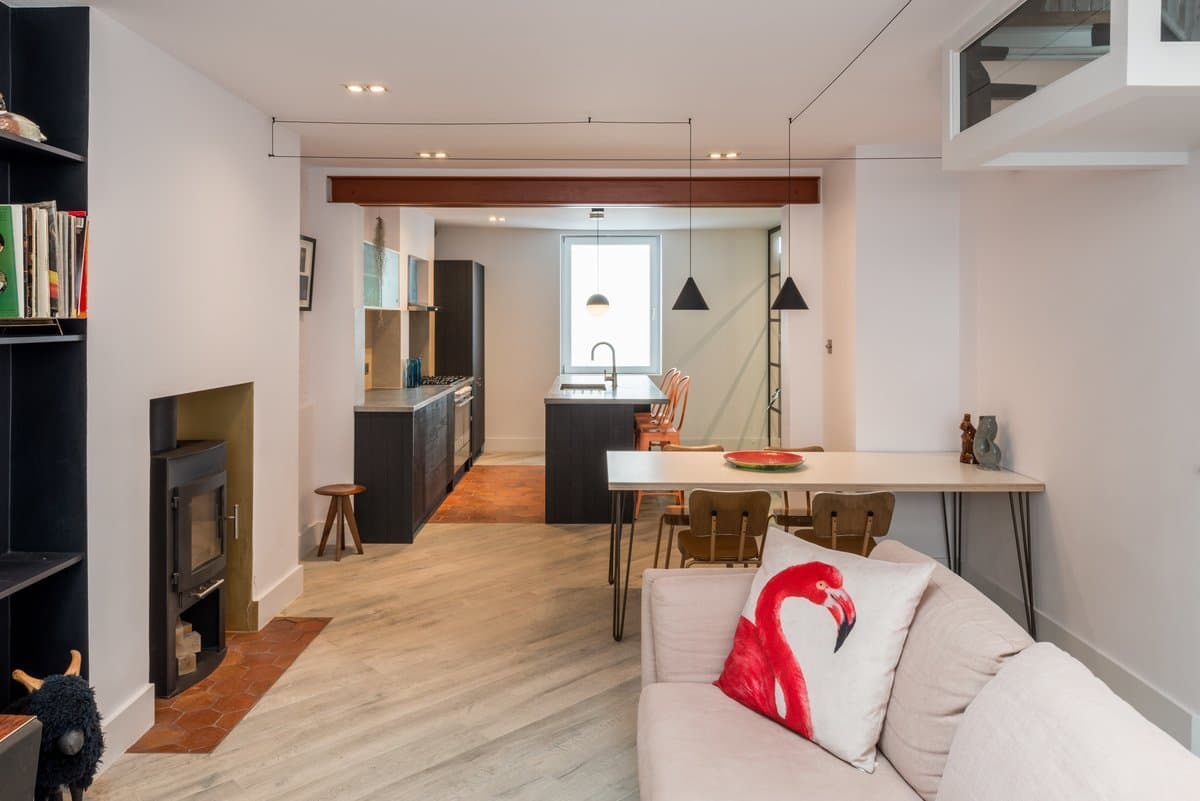 Modern open-concept living space with contemporary kitchen, light gray sofa, and cosy fireplace.