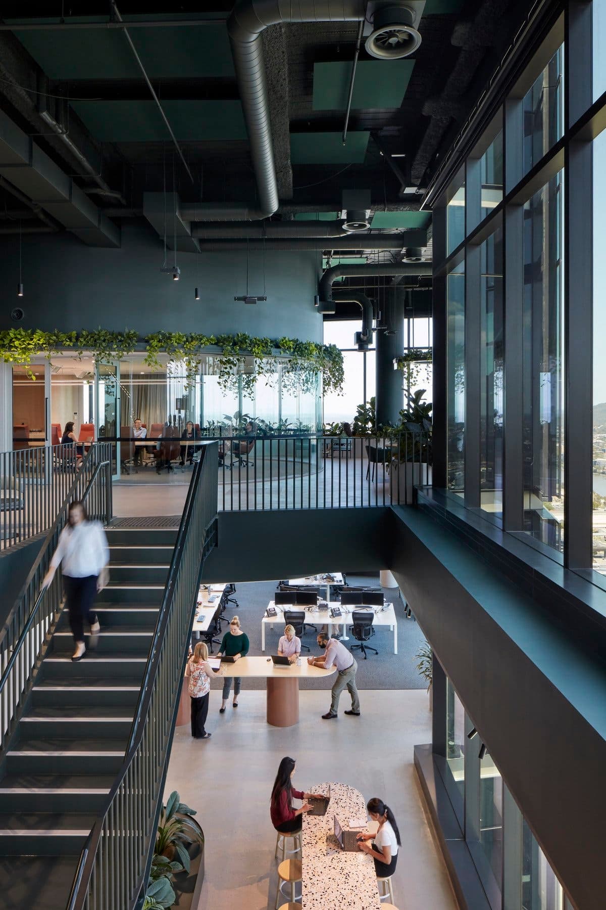 Modern open office with natural light, industrial design, and greenery.