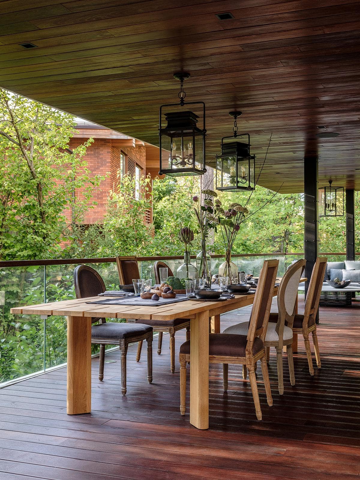 Inviting outdoor dining area with wooden table, comfortable chairs, and lush green surroundings.