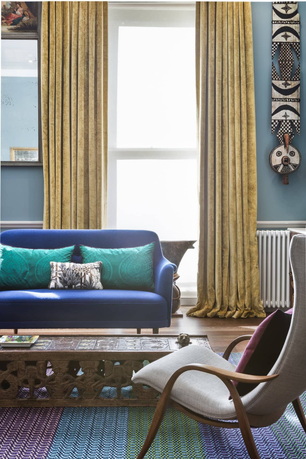 Stylish living room with royal blue sofa, colourful pillows, and mid-century modern decor.