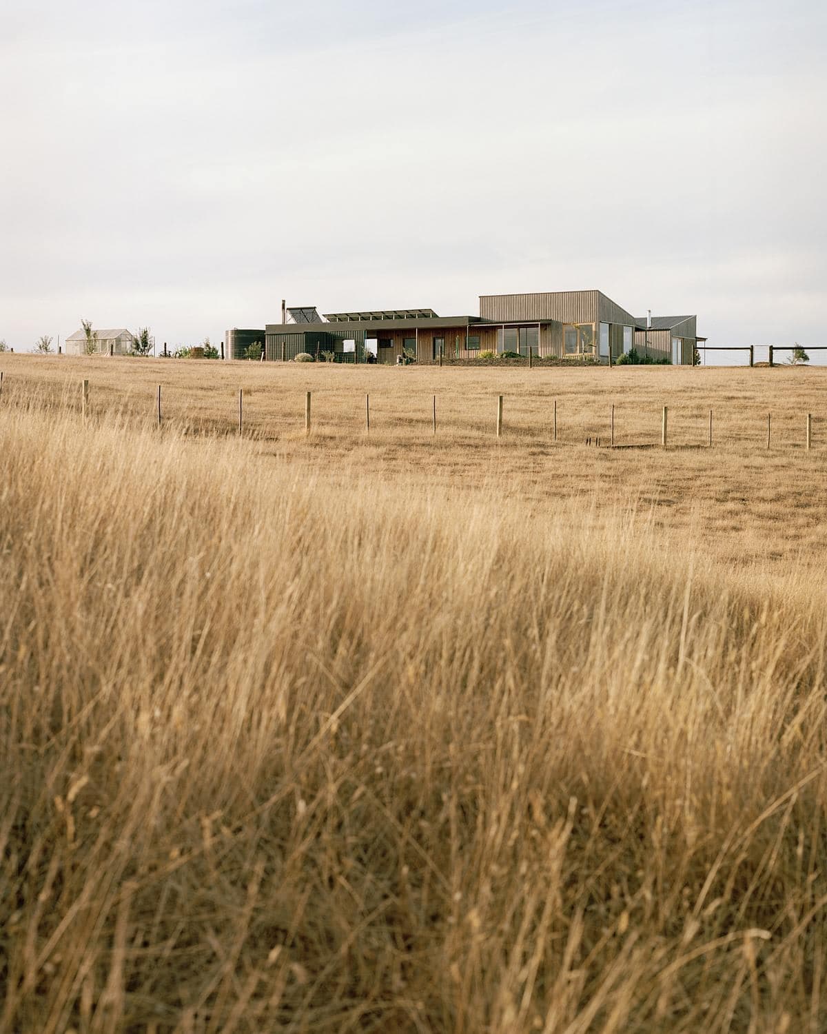 Contemporary home blending with tranquil rural landscape of rolling hills and golden fields.