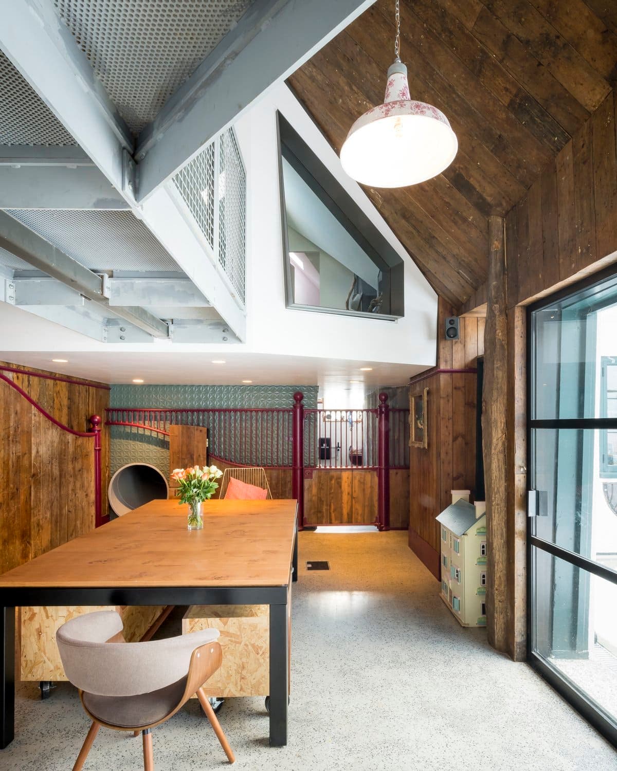 Modern industrial interior with wooden ceiling, concrete floor, and family-friendly play area.