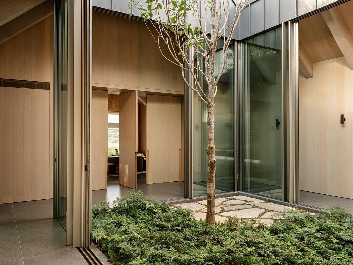 Modern architectural space with serene courtyard, glass walls, and natural wood elements.
