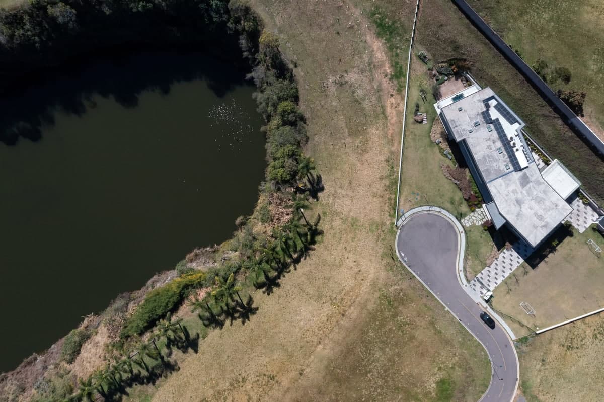 Aerial view of serene pond and modern building amidst lush greenery.