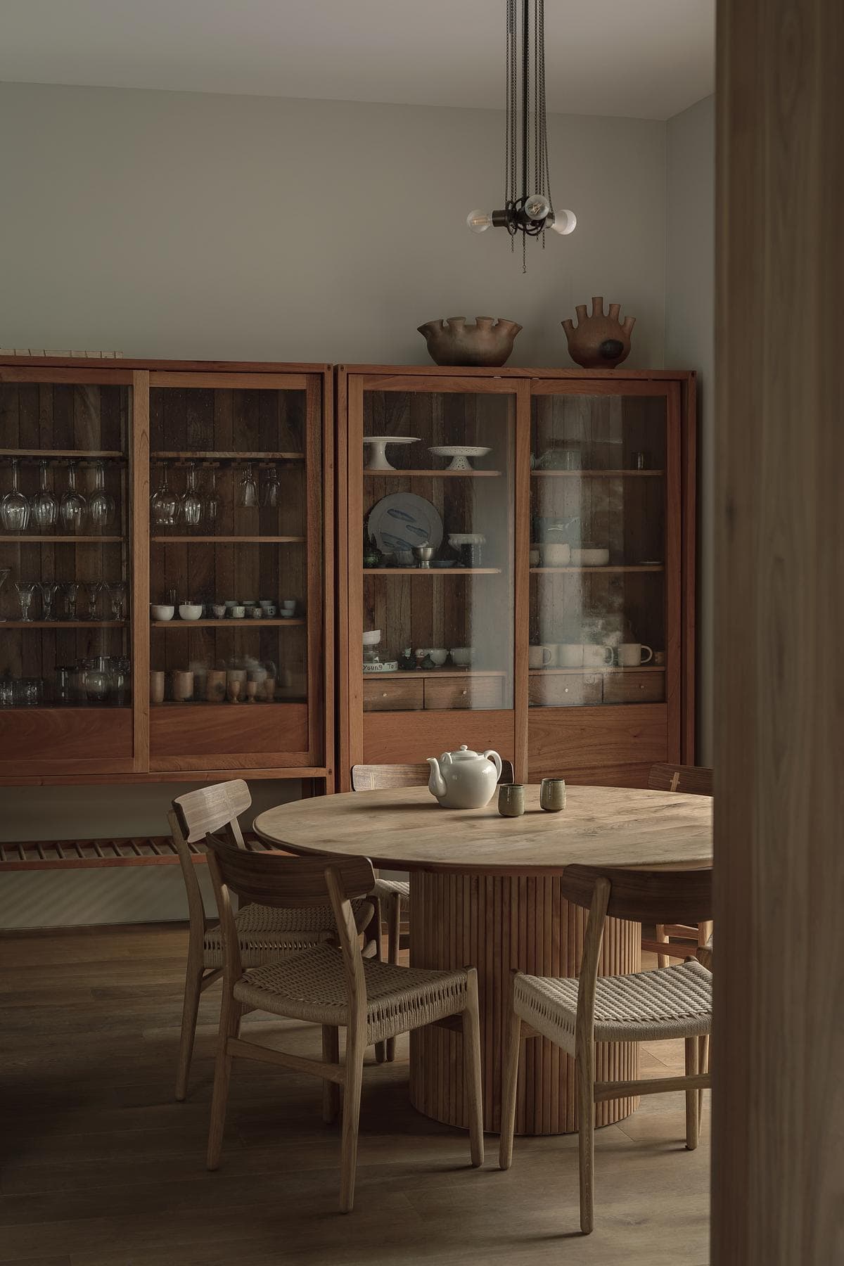 Stylish minimalist kitchen dining area with a round wooden table and dark wood cabinets.