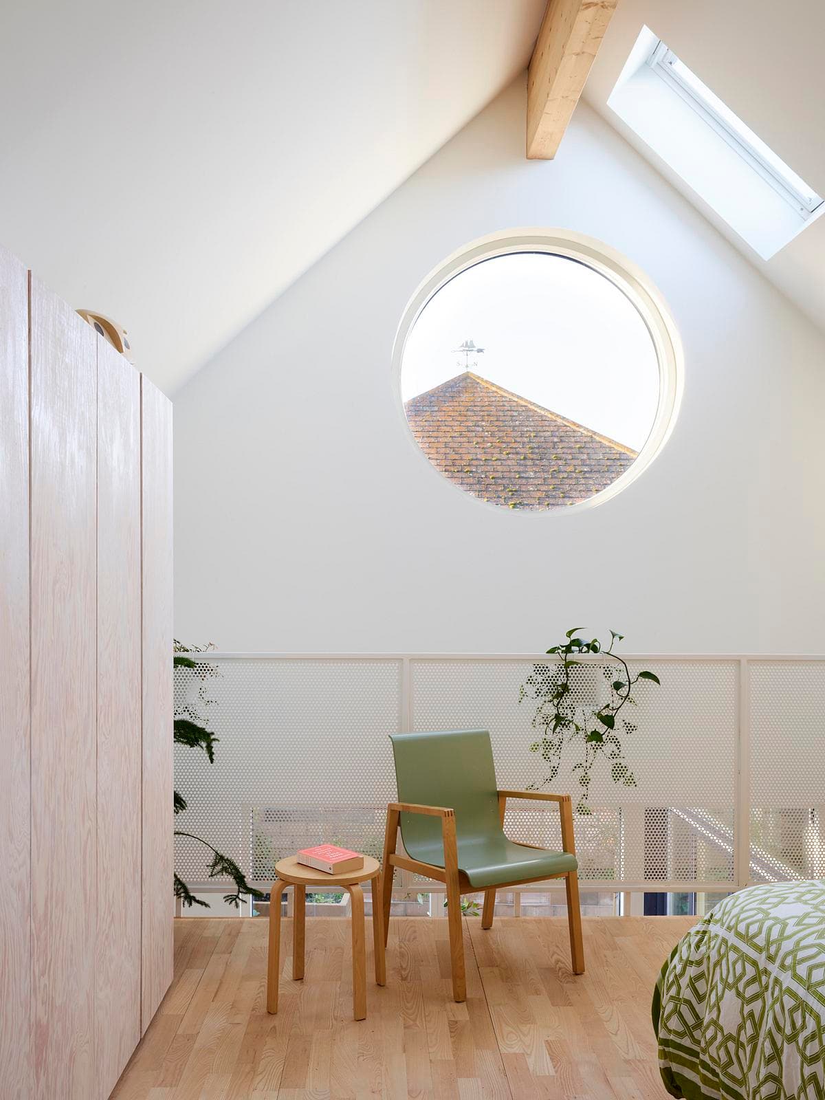 Bright modern loft interior featuring a green chair, natural light, and potted plants.