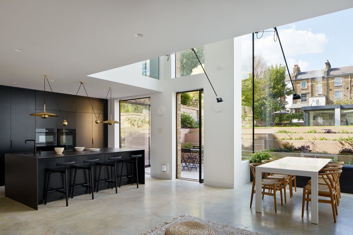 Modern open-concept kitchen and dining area with natural light and black cabinetry.