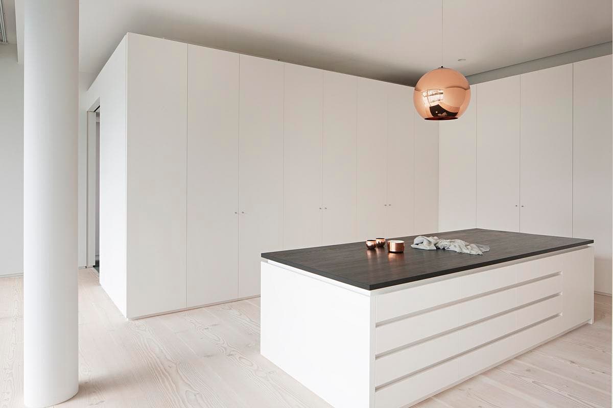 Contemporary white kitchen featuring a dark island, elegant lighting, and minimalist design elements.