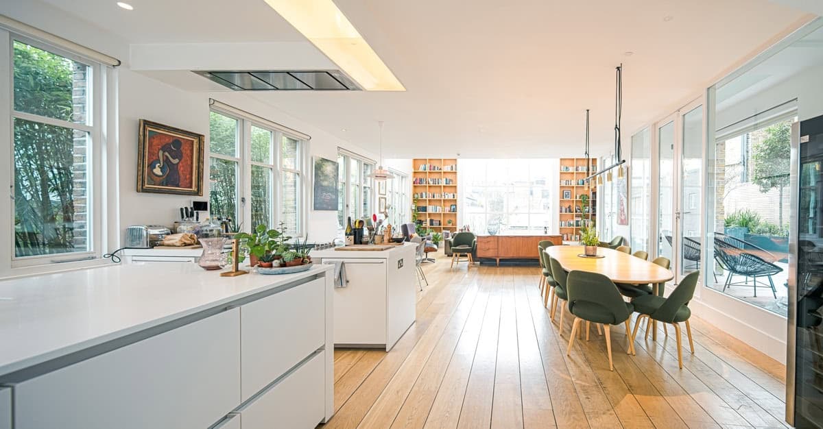 Bright modern kitchen and dining area with large windows and warm wooden flooring.
