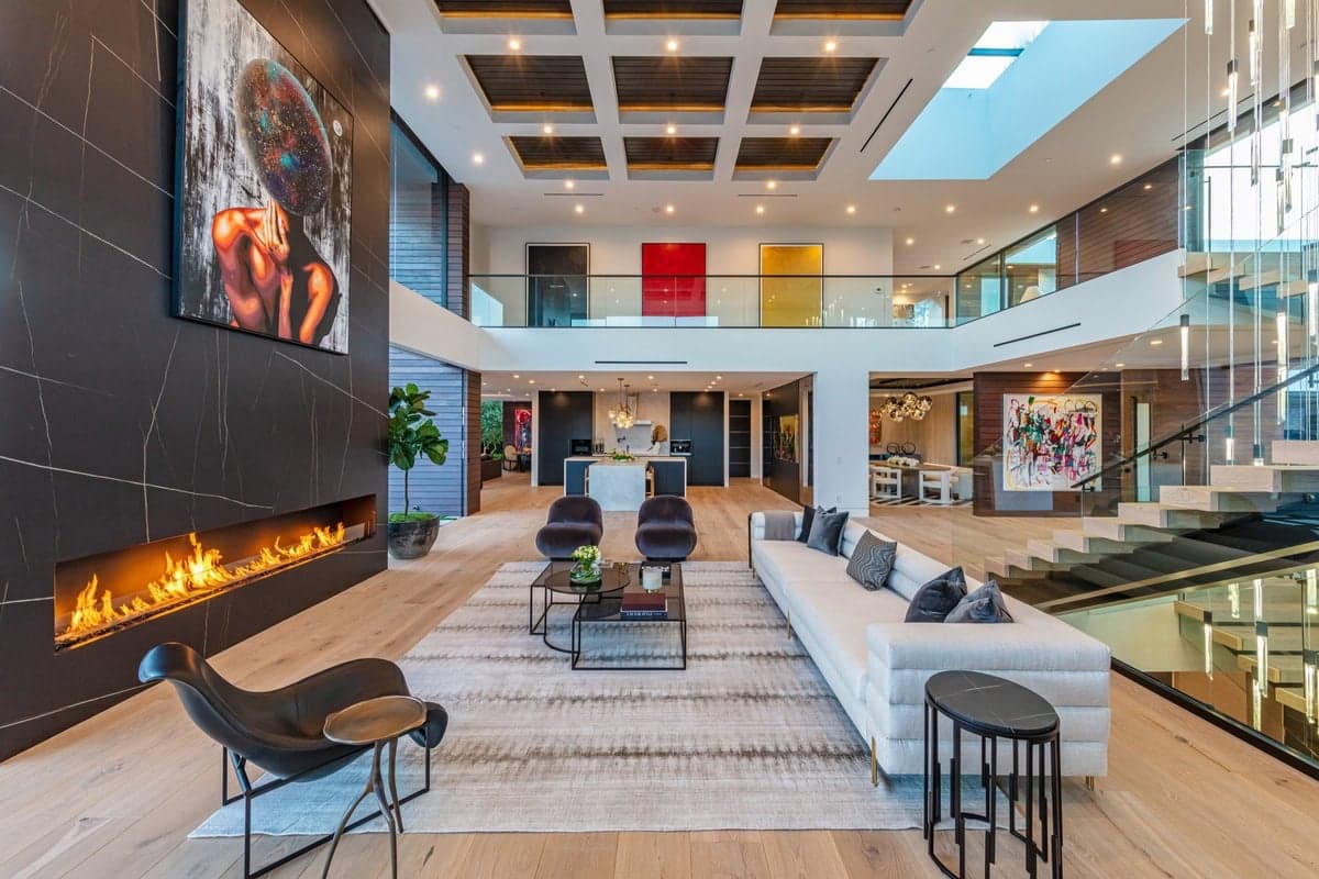 Elegant modern living space with high ceilings, a stylish fireplace, and vibrant artwork.