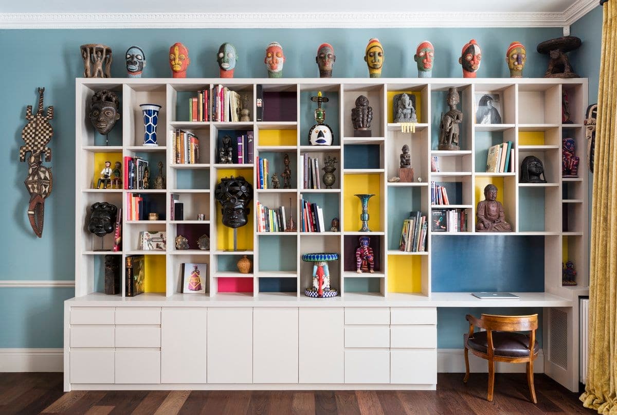 Modern study with white shelving, colourful accents, art pieces, books, and a functional desk area.