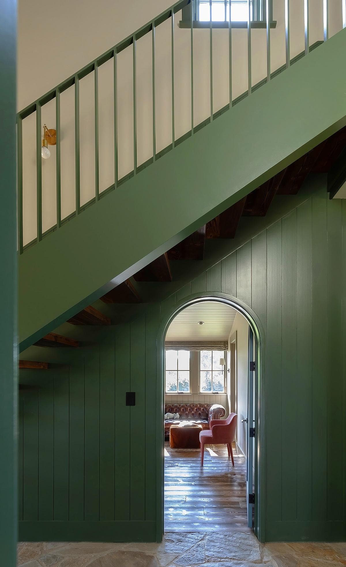 Elegant interior featuring a green wooden railing and inviting arched doorway to a cozy living space.