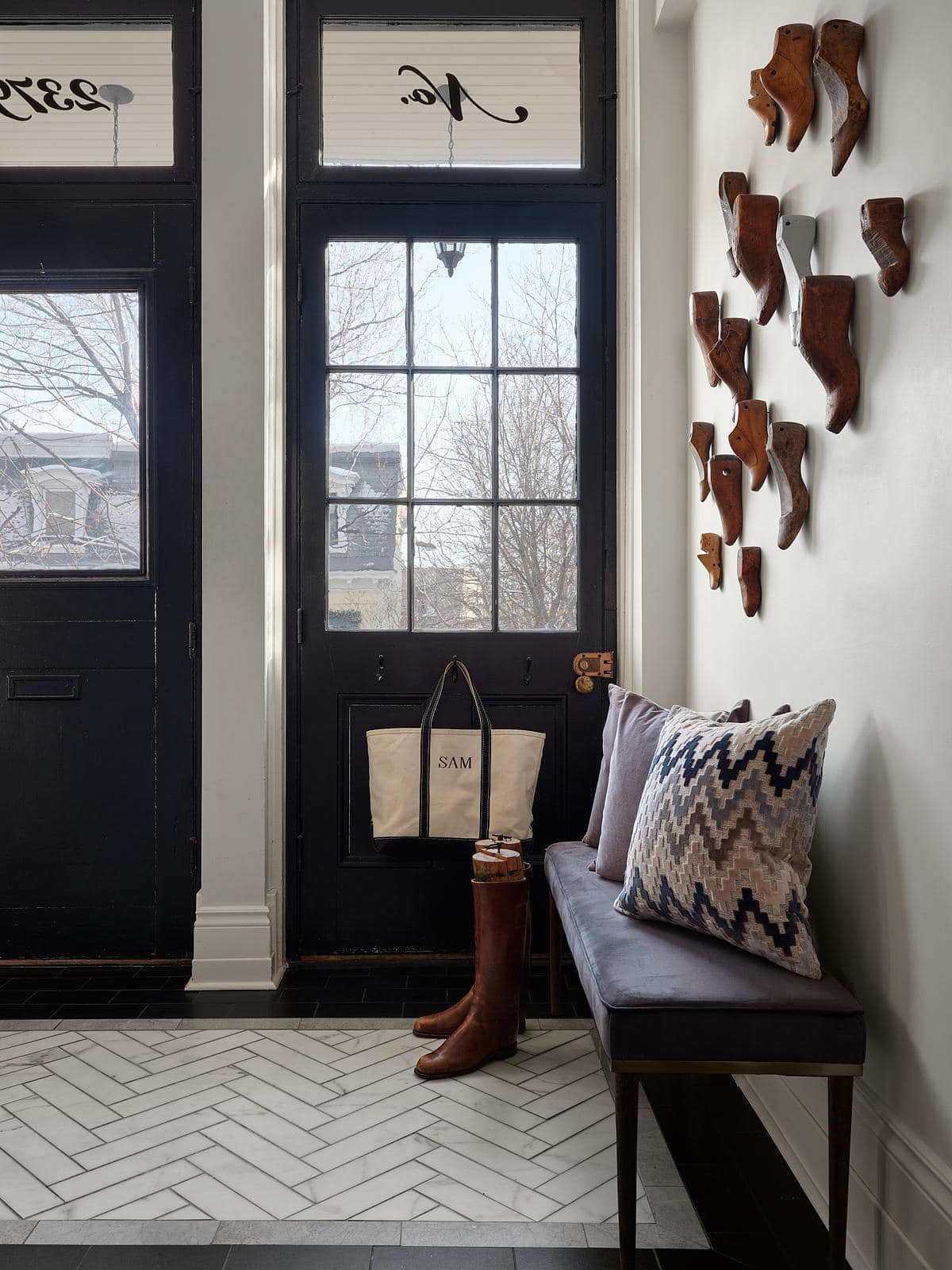 Inviting modern entryway featuring a stylish bench, boots, and artistic wooden sculptures.