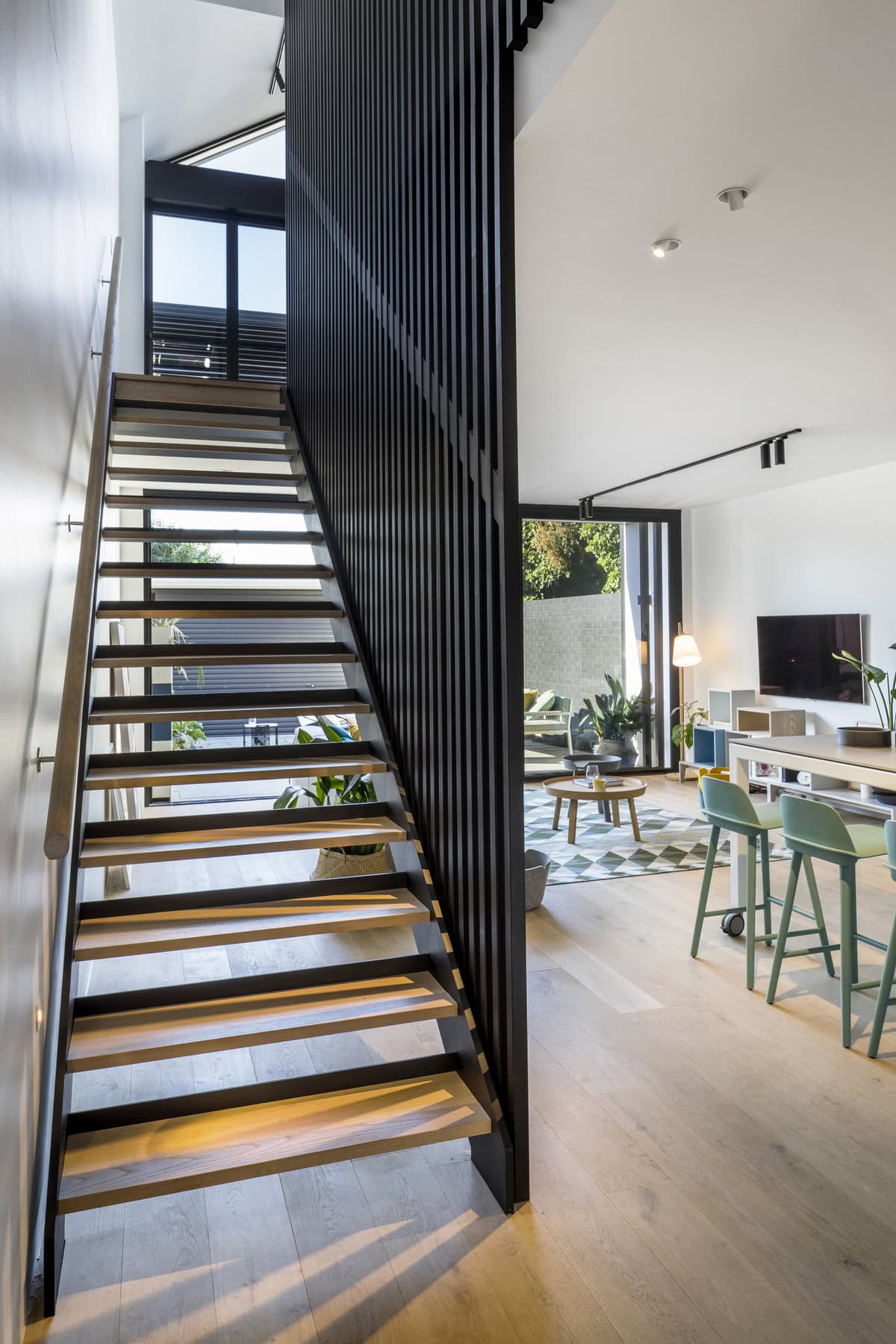 Bright modern interior with open staircase, minimalist decor, and natural light.