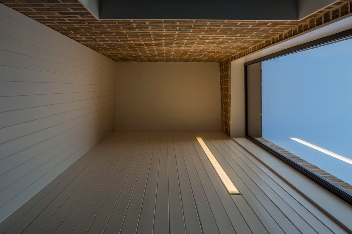 Looking up through a narrow brick shaft with a bright rectangular sky opening.