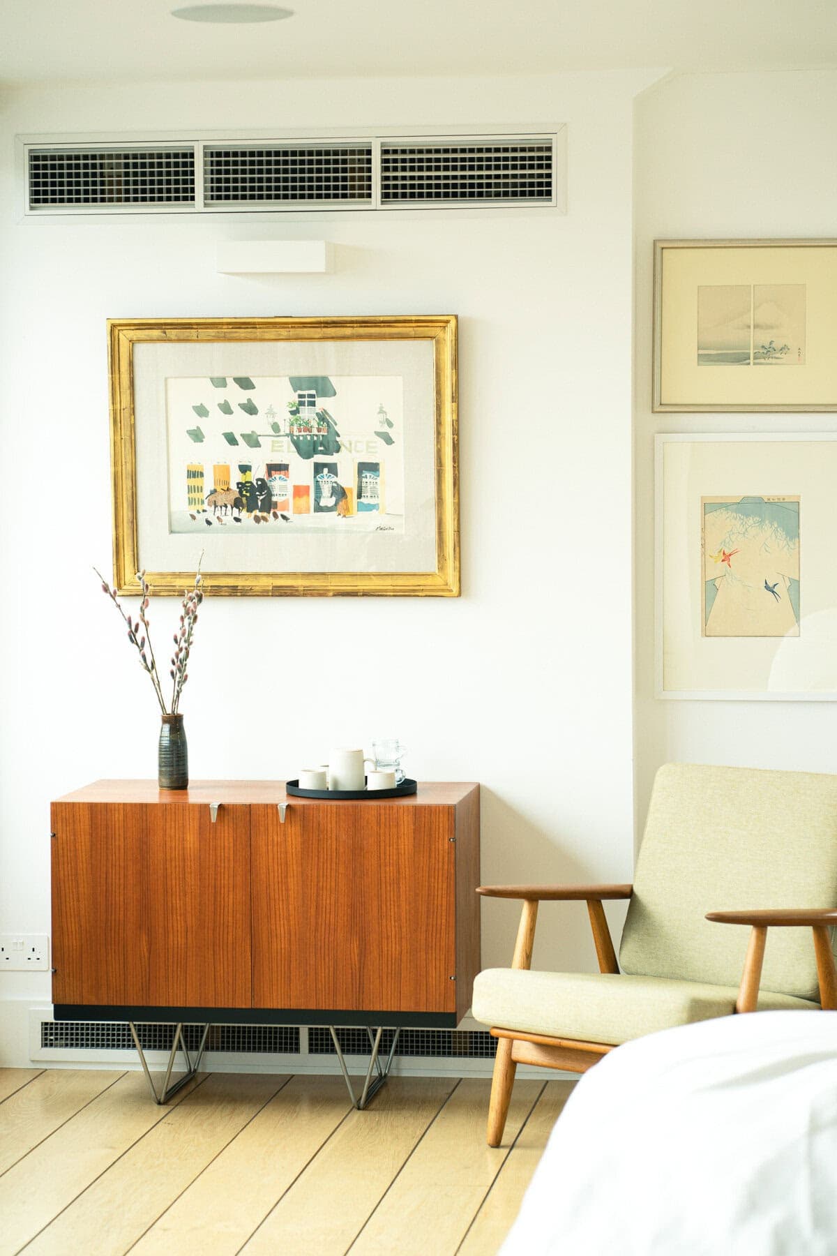 Chic vintage-modern interior with stylish cabinet, art, and comfortable reading nook.