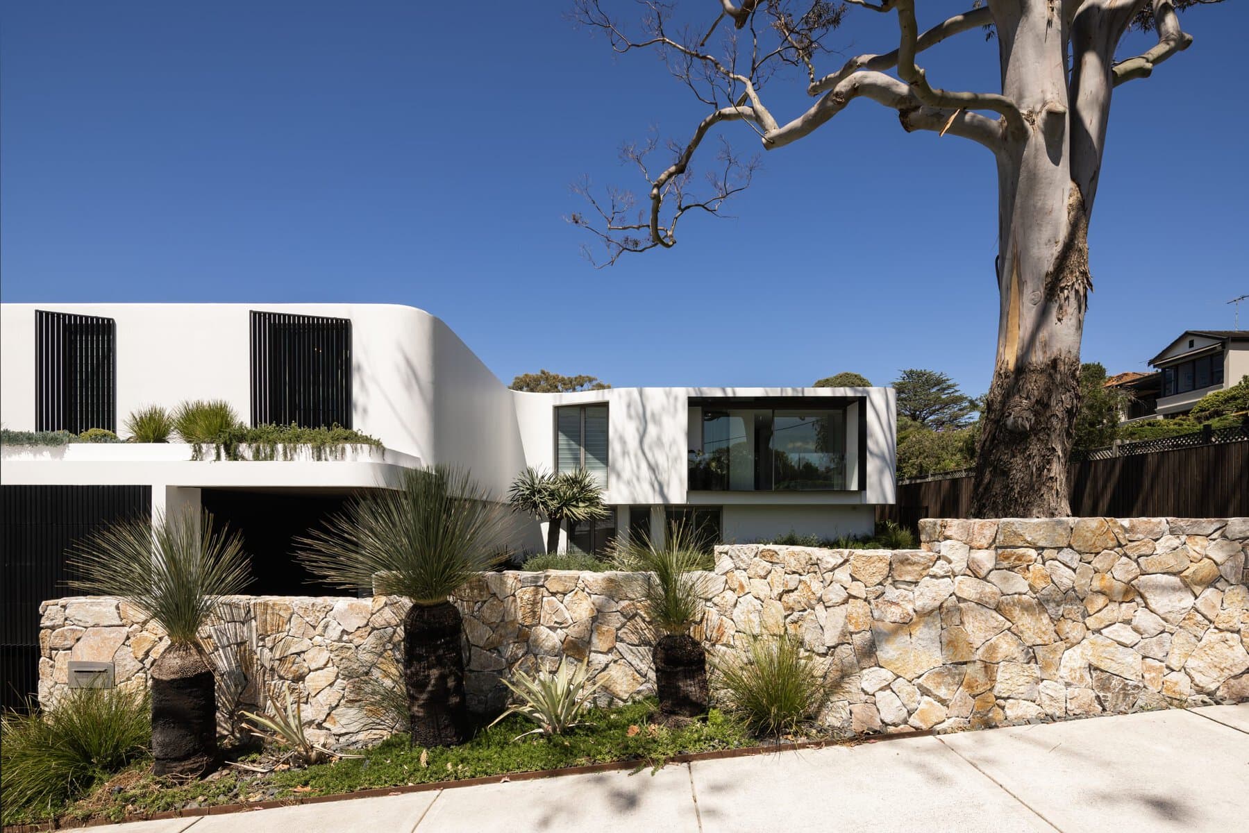 Modern two-story house with white façade, large windows, and minimalist landscaping.