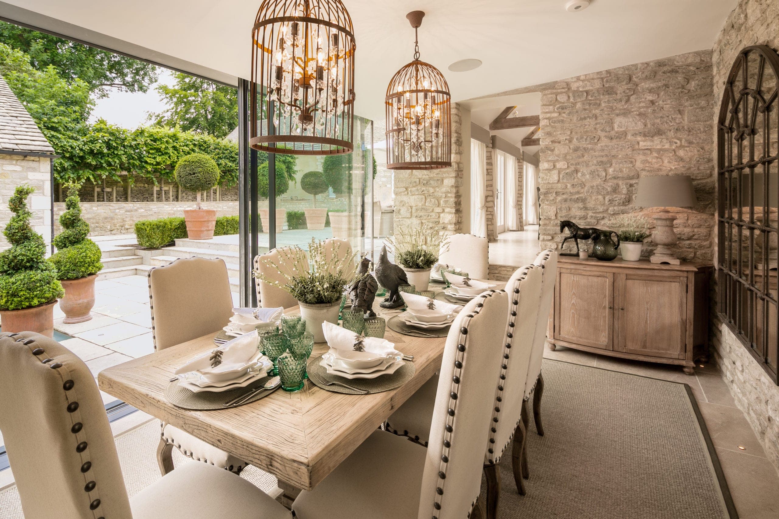 Dining room with birdcage pendants and glass doors open to the courtyard