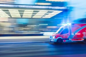 Ambulance speeding through city street at night with flashing blue lights.