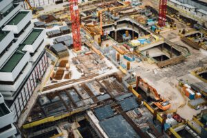 Construction site with cranes, machinery, and workers laying foundations for a new development.
