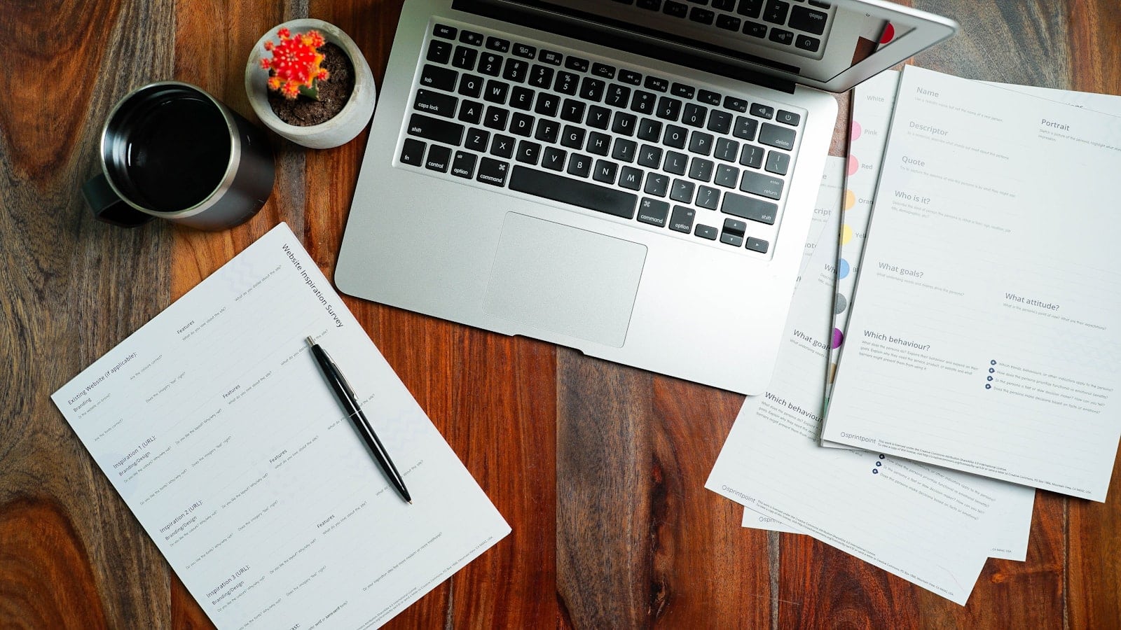 Laptop with notebook and writing materials on a wooden desk
