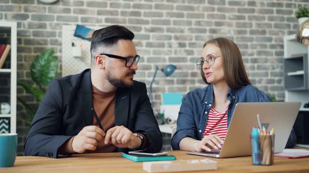 Two professionals reviewing an application on a laptop in an office