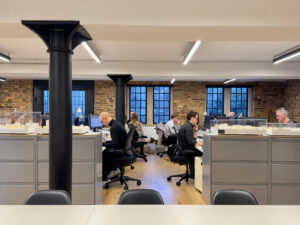Modern industrial office space with open concept, exposed brick, and large windows.