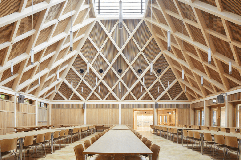 Modern dining hall with wooden beams, skylight, and natural light.