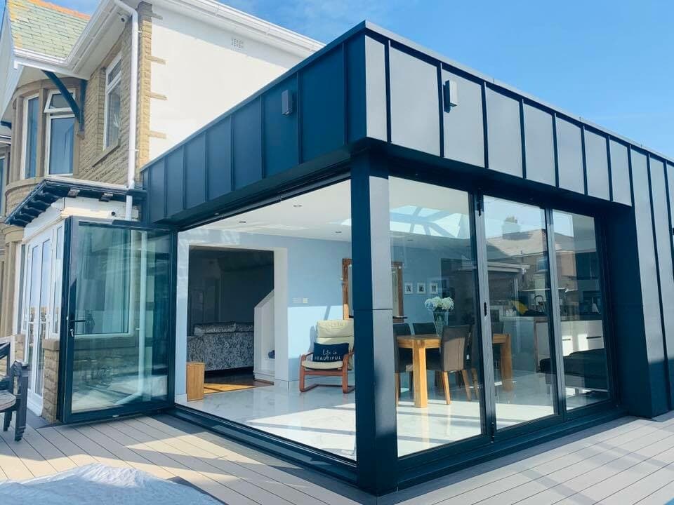 Modern extension attached to traditional house with glass panels and open-plan interior.