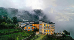 ITC Welcome Hotel: Modern retreat in lush, misty mountain landscape with serene garden paths and views.