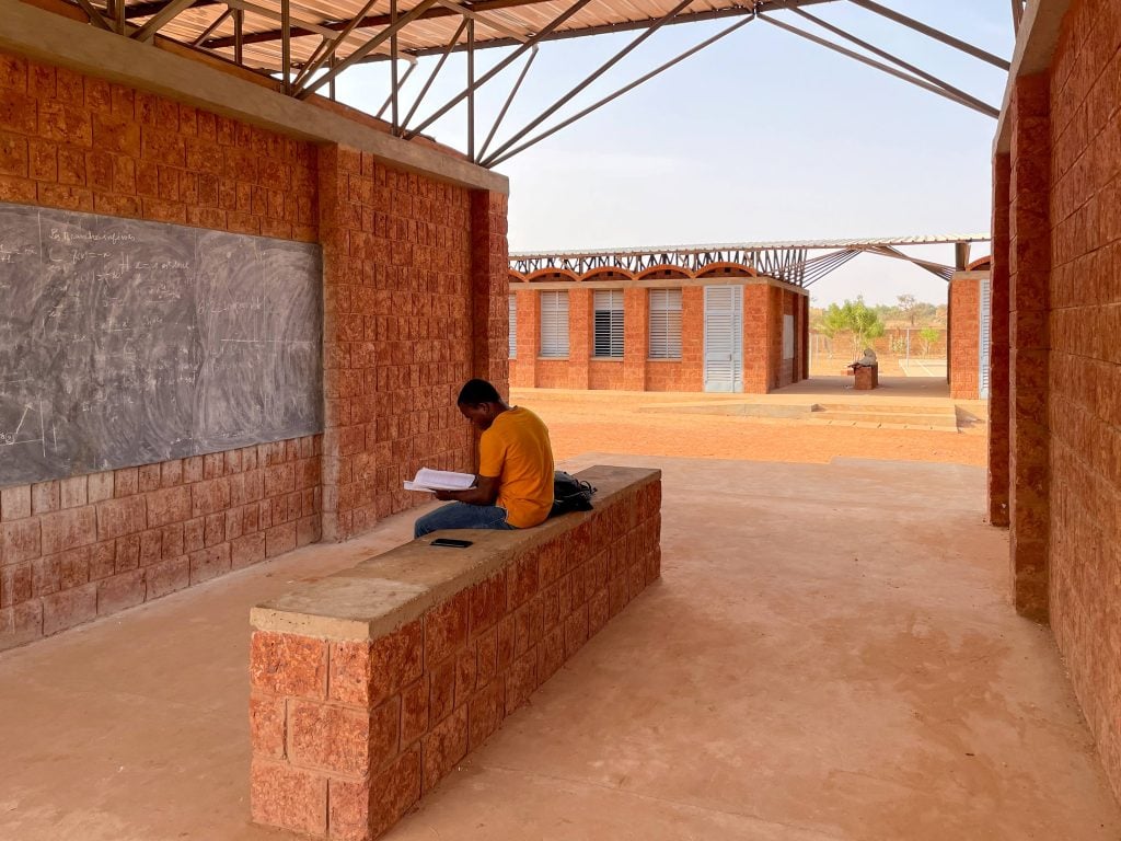 Focused student in an innovative learning environment with natural light and brick architecture.