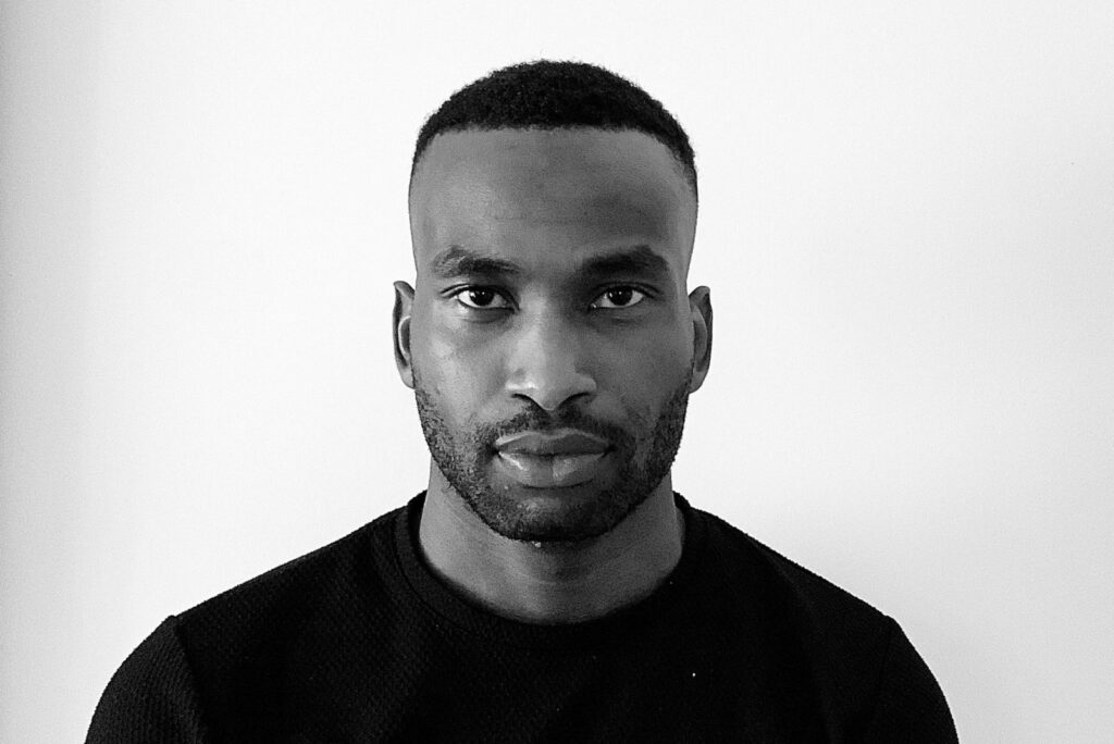 Black-and-white portrait of Muyiwa Oki, serious expression, intense gaze.
