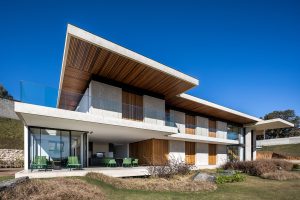 Modern two-story house with expansive glass, wooden accents, and a spacious outdoor patio.