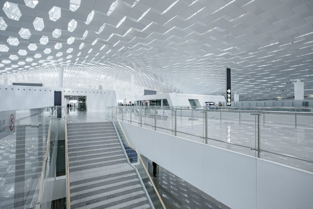 Modern airport interior with geometric ceiling and glass railings, highlighting a spacious and bright design.